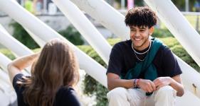 A student sitting on top of a bench outside of Richmond Building