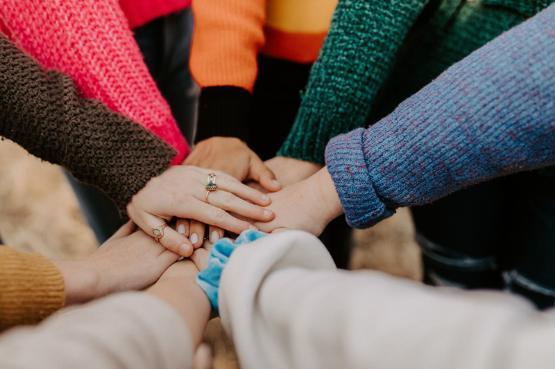 Eight hands coming together, stacking on top of each other.