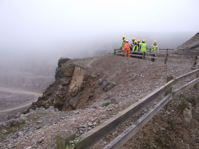 Students wearing high-vis jackets and hard hats standing at a rock face in Whitby.