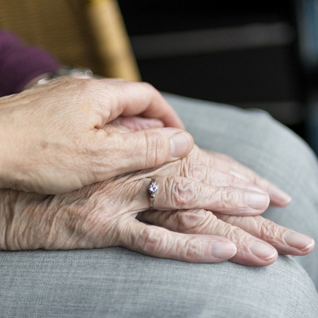 A hand of a carer placed on an elderley hand to show their support