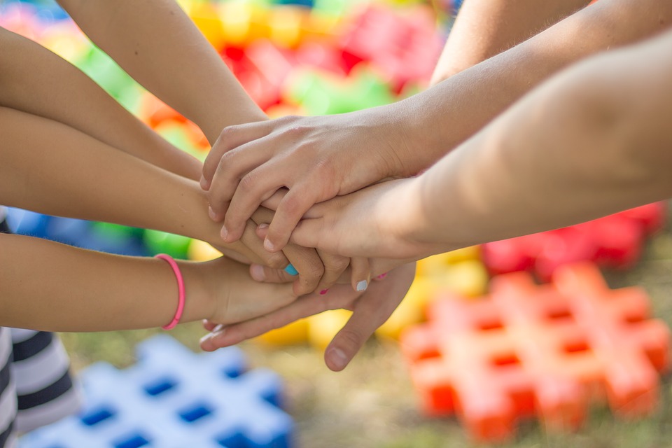 Many hands on top of eachother in a circle, signifying working together as a team.