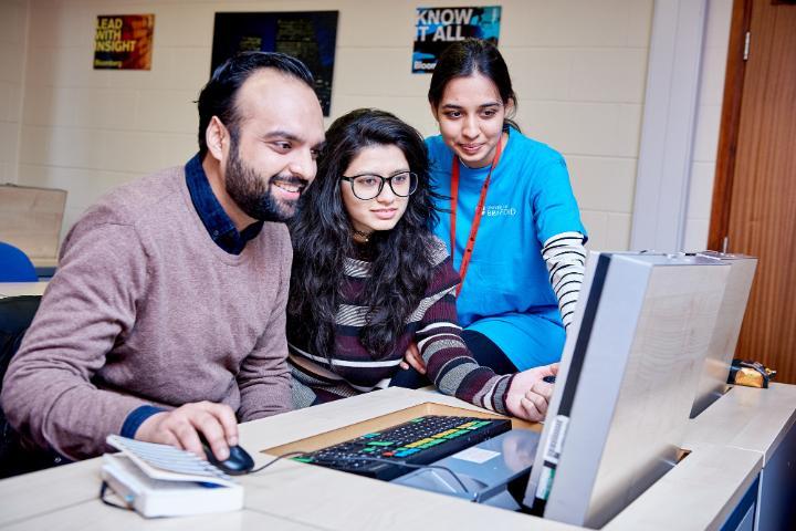 3 students work together in Bloomberg Trading room for Career Booster Training session