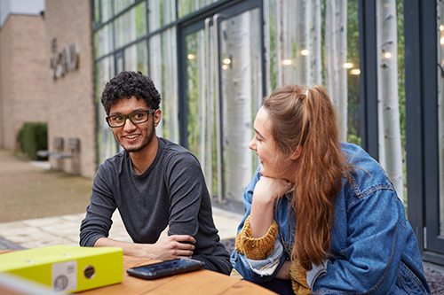 Two students sat outside The Orchard chatting