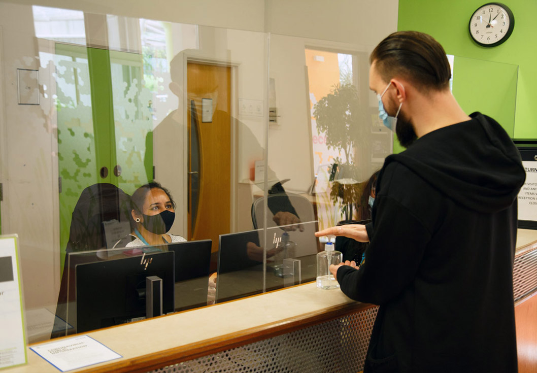 A member of staff dispensing hand sanitiser from a pump bottle at the entrance to the Richmond building