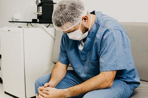A doctor sitting with his head down during a difficult day 