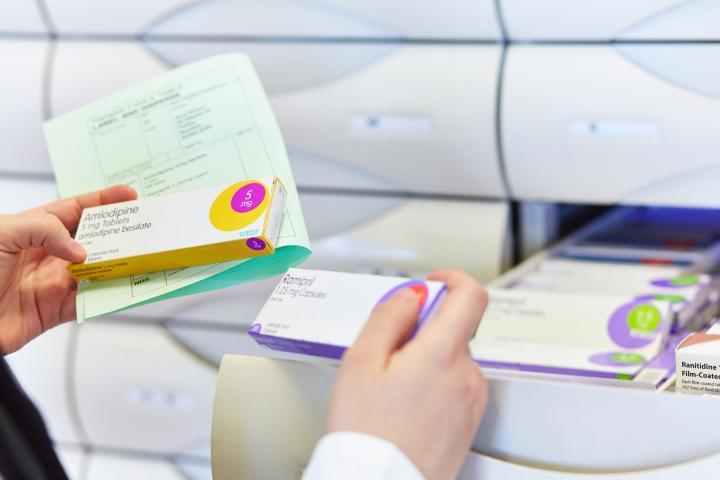 A student handling medication boxes out of drawers in a lab.