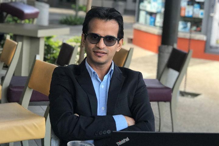 MBA student Shabeel Maudarbaccus sitting at a table with his arms crossed