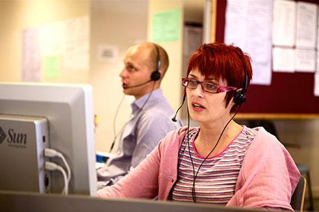 Two members of staff wearing headsets taking phonecalls
