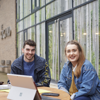 Three students sat outside the student lounge smiling